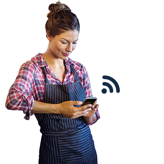  Individual wearing work attire using a smartphone to manage kitchen appliances via Smartconnect, shown with wireless icon, representing digital connectivity and efficient device management for foodservice operations.